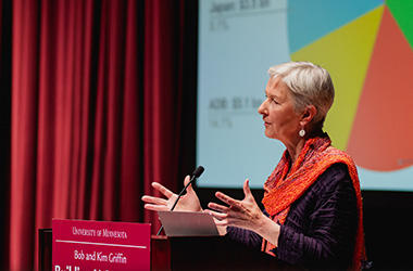 Deborah Brautigam delivering the Griffin Lecture in front of a slideshow and red stage curtain